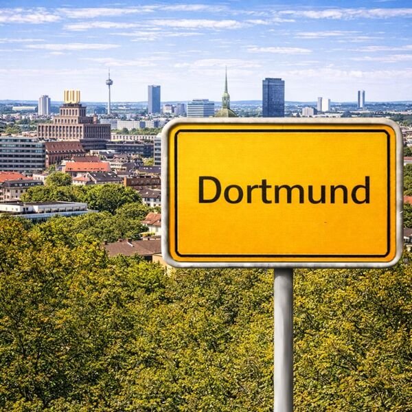 Gelbes Ortsschild Dortmund mit Stadt im Hintergrund
